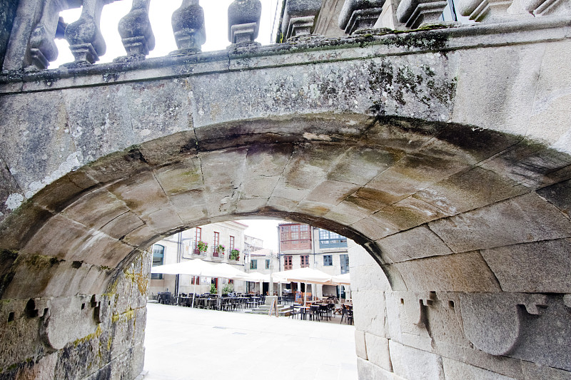 Le?a,square',Plaza,de,la,le?a'seen,from,under,a,stone,footbridge,with,baluster.,,,Pontevedra,city,,Galicia,,Spain.,Cruceiro,,stone,cross,in,the,middle.,Traditional,architecture,,galerias.