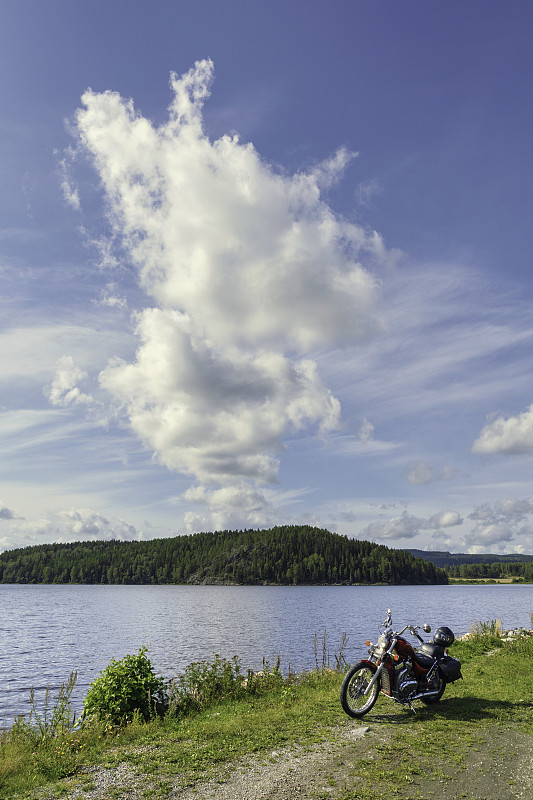 A,motorcycle,parked,by,the,shore,of,a,lake,on,a,summer,day,,on,the,countryside,of,the,V?rmland,province,in,Sweden.