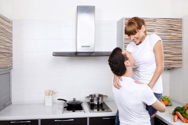 在家里拥抱在厨房里的年轻夫妇