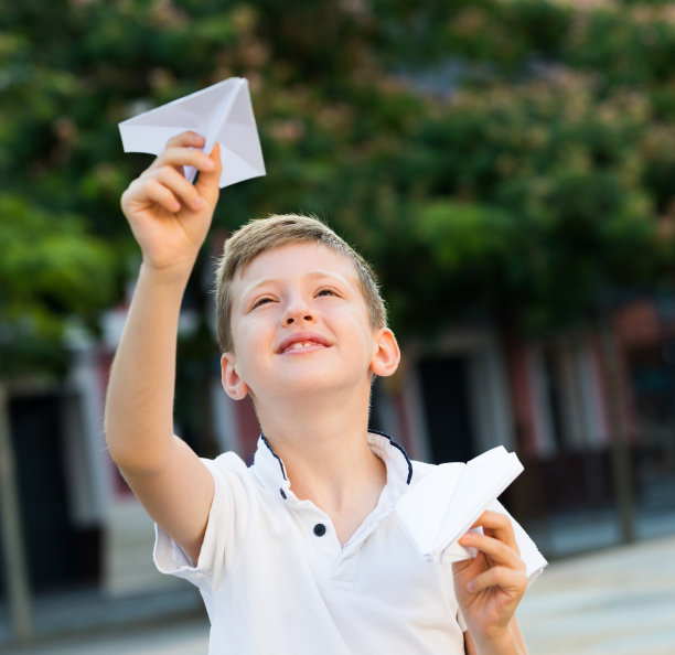 在公园里玩纸飞机的小男孩