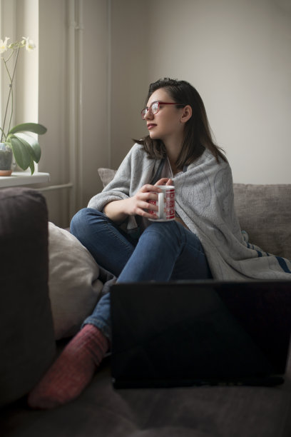 女人坐在家里的沙发上透过窗户看