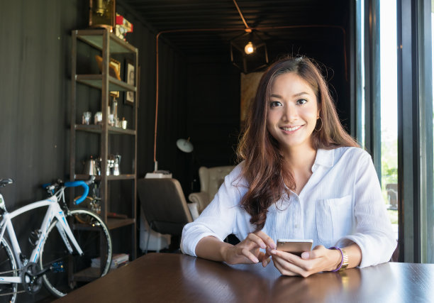 年轻女子看咖啡店使用手机