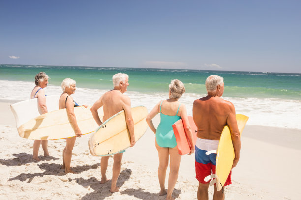沙滩上拿着冲浪板的老年妇女