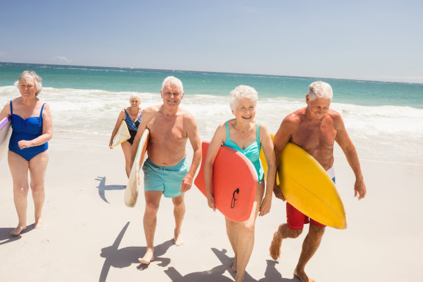 沙滩上拿着冲浪板的老年妇女