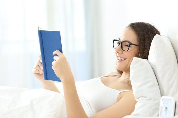 年轻女子躺在床上看书