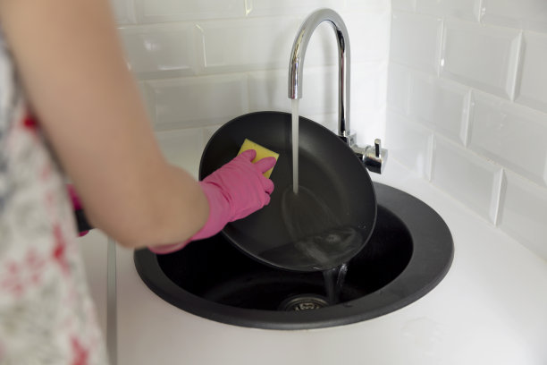 妇女戴手套洗餐具