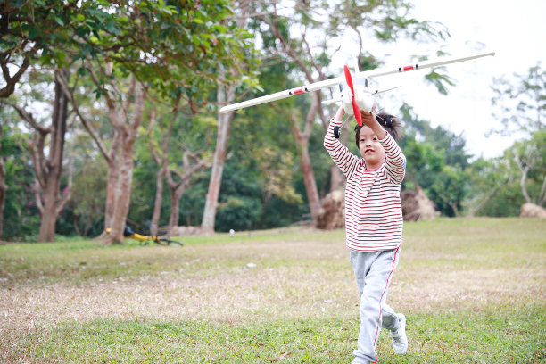 在公园里玩纸飞机的小男孩