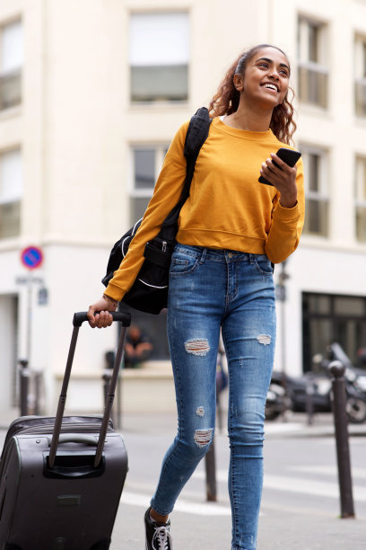 年轻女子拉着行李使用手机