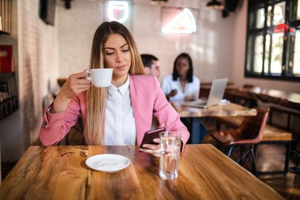 年轻女子看咖啡店使用手机