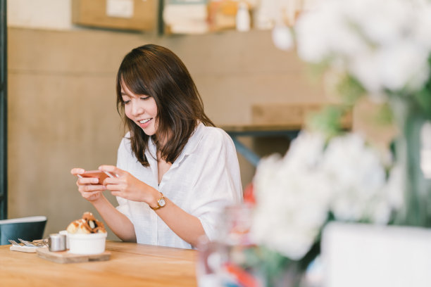 年轻女子看咖啡店使用手机