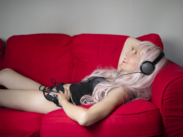漂亮的金发美女躺在沙发上听音乐