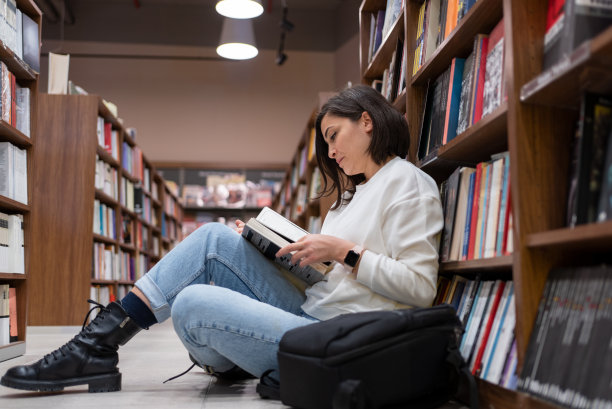 坐在图书馆地板上看书的女大学生