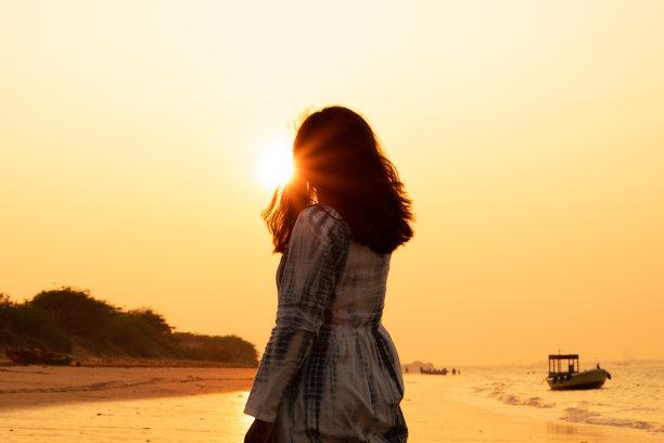 在日落的心情中享受海上假期自由的女人