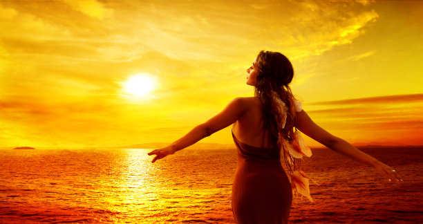 在日落的心情中享受海上假期自由的女人