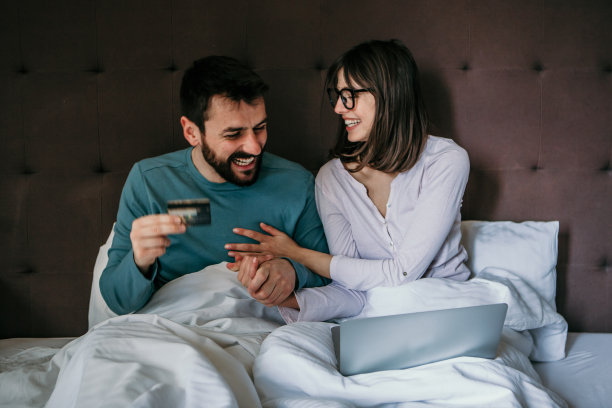 年轻夫妇在卧室的家里床上用电脑