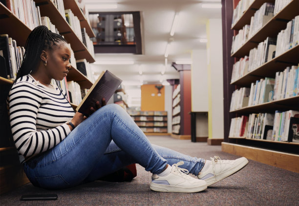 坐在图书馆地板上看书的女大学生