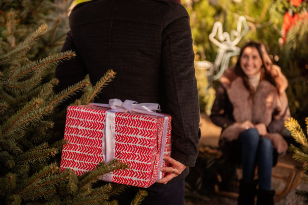 圣诞树下幸福的男人和女人拿着礼物