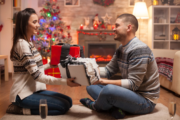 圣诞树下幸福的男人和女人拿着礼物