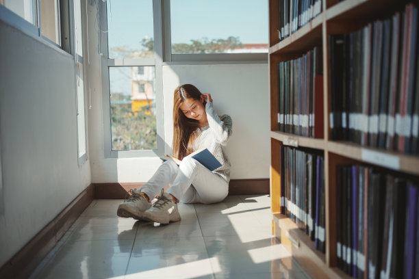 坐在图书馆地板上看书的女大学生