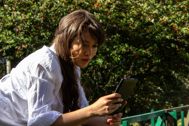 年轻女子在公园使用平板电脑