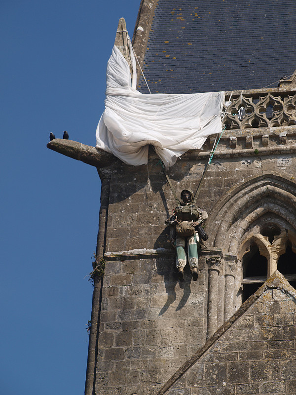 church,in,Sainte-Mère-église,,with,the,dummy,of,a,paratrooper,John,Steele,,with,a,parachute,caught,on,the,spire,of,the,town,church,during,D-day,in,Normandy,,world,war,2