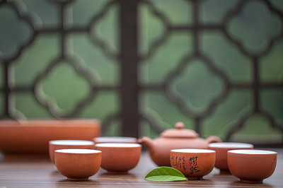 月光下窗花旁桌上的中国茶壶和茶杯富有禅意