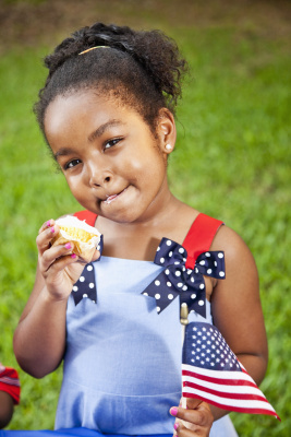 小女孩拿着美国国旗吃纸杯蛋糕