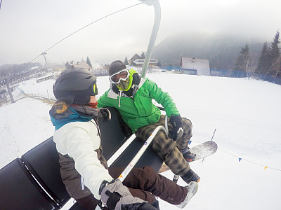 年轻女子和成年男子一起乘坐滑雪缆车