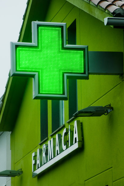 街道上的药店标志，绿色十字和绿色房屋立面的细节。