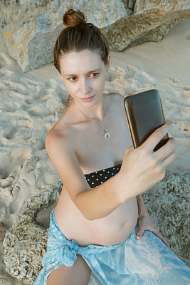 孕妇在海滩上自拍，在暑假期间怀孕