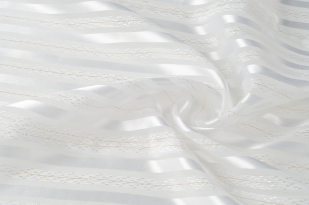 背景纹理、图案。白色的丝质织物，带有一条带。波纹白色丝绸织物的特写。柔滑优雅的金丝可作为婚礼背景。复古的风格