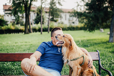 盖伊和他的狗，金毛猎犬，在城市公园。