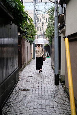 在一个雨天，在东京神乐坂传统老城的小巷里走着的女人的背影