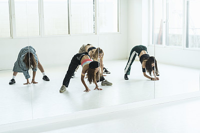 年轻女舞者在舞蹈工作室伸展身体。