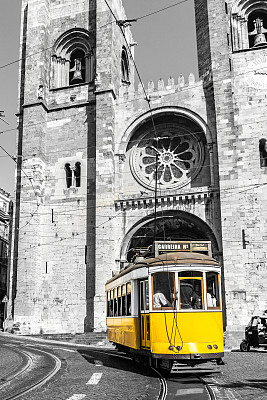 古老的黄色电车在里斯本大教堂前。黑白照片，只有有轨电车的彩色。