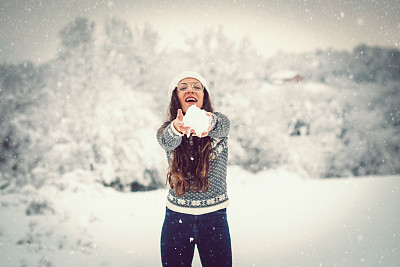 穿着毛衣的女人在冬天打雪仗