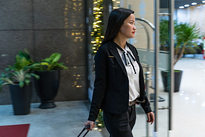 年轻的亚洲商务女性在出差时走进酒店大堂 年轻的亚洲商务女性在出差时走进酒店大堂
