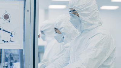 一组科学家穿着无菌防护服在现代工业3D打印机器上工作。制药、生物技术和半导体制造工艺。