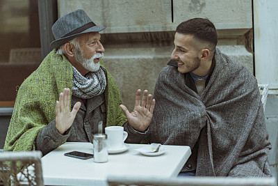 老人和他的孙子在喝茶