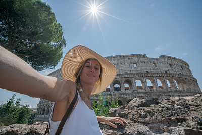 一名年轻女子在罗马享受意大利旅行的自拍，并在著名的罗马斗牛场前拍摄了一张照片