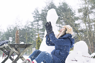 女人喜欢雪，在树林里堆雪人