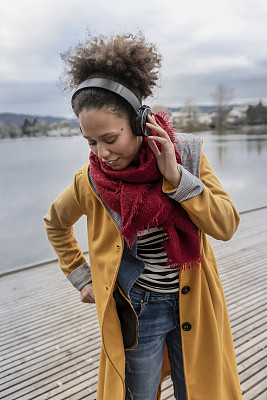 迷人的混血女人听音乐在户外使用耳机