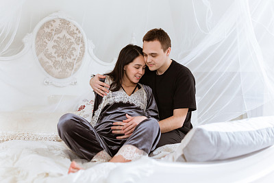 幸福的夫妇和怀孕的妇女在家里的早晨肖像