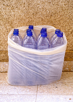 石头墙附近的塑料袋里装着空塑料瓶。