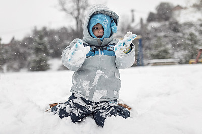 可爱的蹒跚学步的小男孩在雪中玩耍