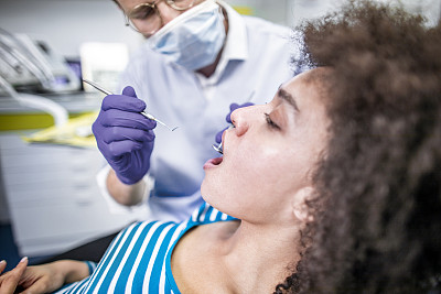 牙科检查-牙医使用挖掘机镰刀探针和口镜对病人进行牙科检查