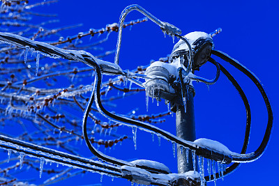 电器箱安装，电线上挂有水晶冰柱。天气在北美冬季灾难。寒冷的加拿大春天的冰雪灾难。