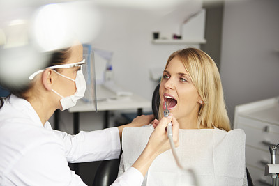 专注的牙医用牙钻清洁病人的牙齿