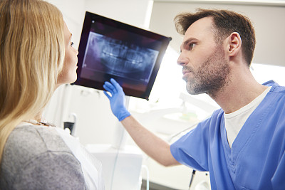 牙医指着x光检查病人的牙齿