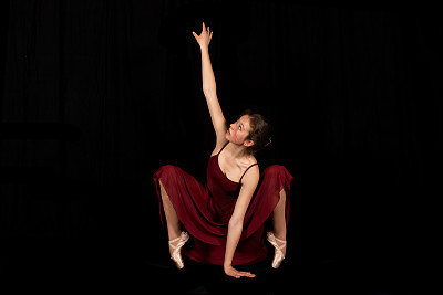 年轻的芭蕾舞演员在黑色背景上跳舞